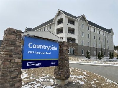 A multi-story building with a sign in front reading "Countryside, 2307 Algonquin Road, Extendicare" on a partially snow-covered lawn.