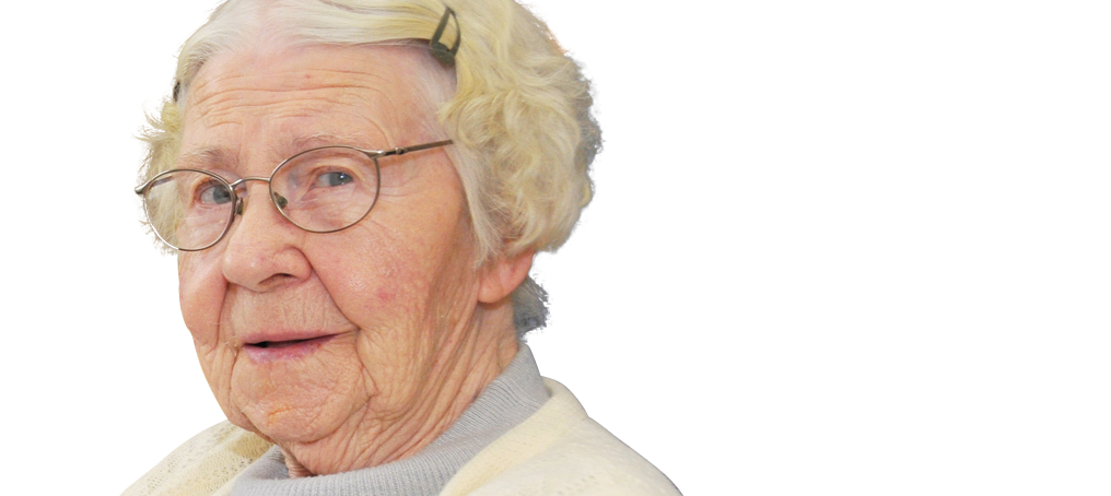An elderly woman with light hair, glasses, and a white sweater looks slightly to the side against a plain white background.