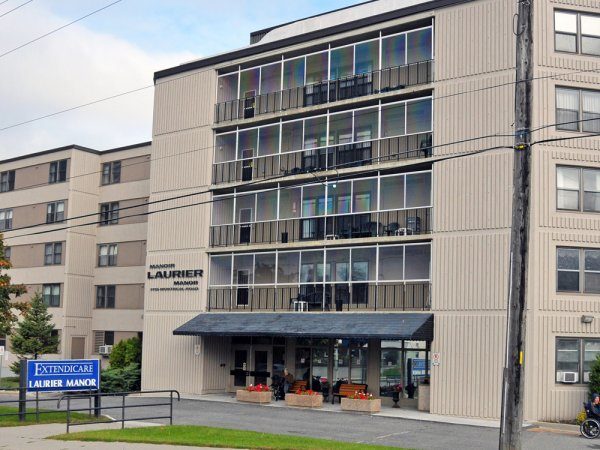 A multi-story beige building labeled "Laurier Manor" with balconies and a blue "Extendicare Laurier Manor" sign near the entrance.