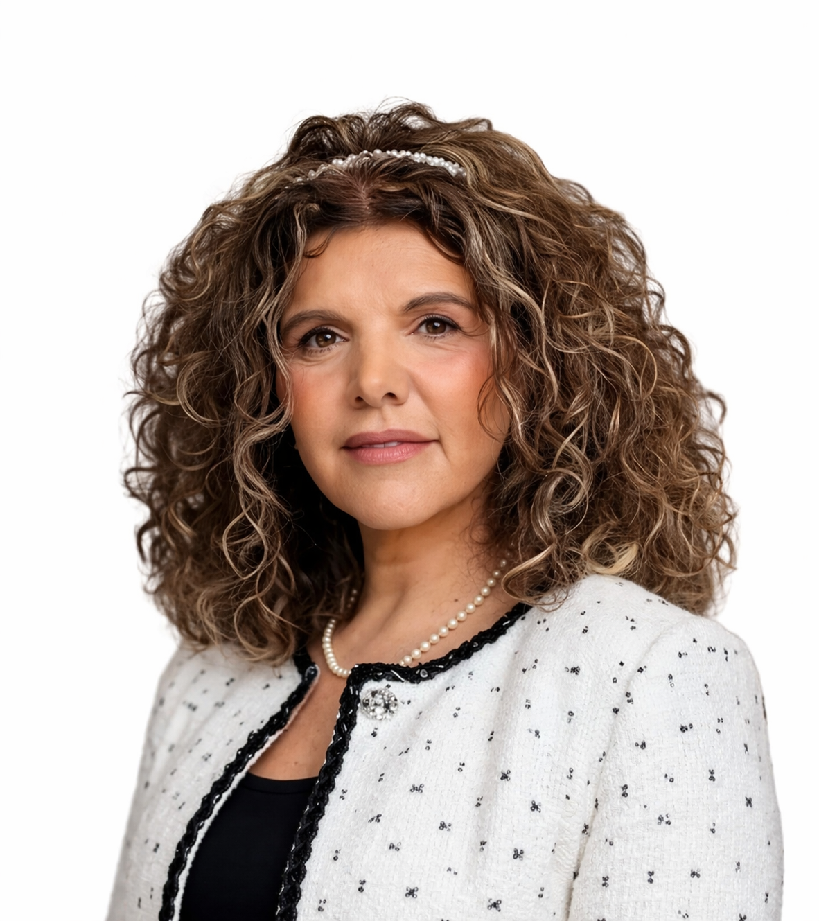 Woman with curly brown hair wearing a white textured blazer and a black top, posing against a plain white background, exemplifying the professionalism of the Extendicare leadership team.