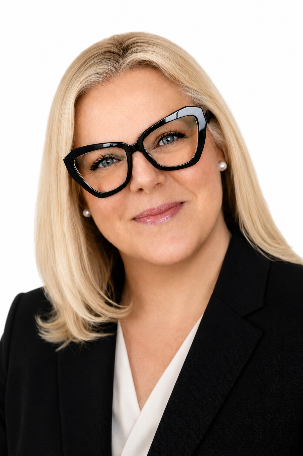 Woman with straight blonde hair, wearing large black glasses, a black blazer, and a white blouse, smiling at the camera against a white background as part of the Extendicare leadership team.